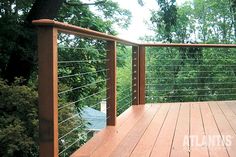 a wooden deck with metal railing and trees in the background