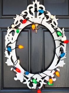 a wreath with christmas lights hanging from it's sides on the front door,