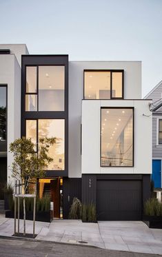 a modern house with black and white sidings on the front, windows in the back