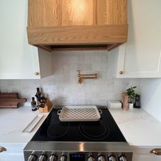 a stove top oven sitting inside of a kitchen next to a wooden cabinet above it