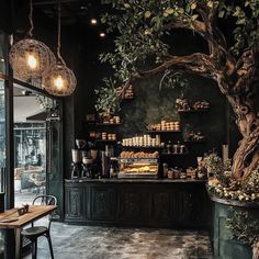 the interior of a coffee shop with plants and lights hanging from the ceiling over the counter