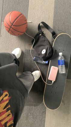 a skateboard, basketball and water bottle on the ground