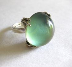 Chunky moonstone ring that changes colors (light green, dark green, light blue).  Silver tone setting and band, size 6.  In good vintage condition. FREE SHIPPING IN THE USA ONLY. Vintage Green Oval Opal Ring, Vintage Green Opal Ring, Adjustable Green Opal Ring, Vintage Green Opal Round Ring, Green Moonstone Round Jewelry, Green Cabochon Moonstone Ring Gift, Green Cabochon Moonstone Ring, Unique Adjustable Green Opal Ring, Vintage Moonstone Crystal Ring