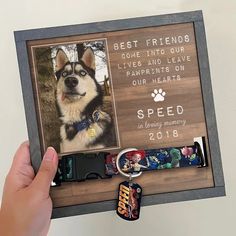 a hand holding a dog memorial frame with a keychain attached to it and a paw print on the front