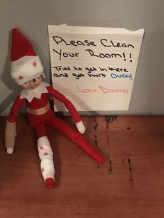 an elf doll sitting next to a sign that says please clean your room