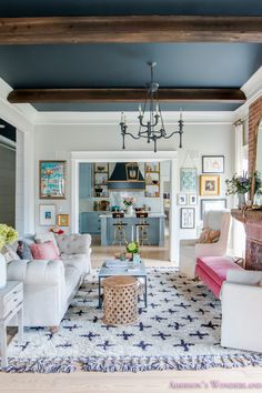 a living room filled with furniture and a chandelier hanging from the ceiling in front of a fire place