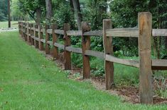 a wooden fence is lined with green grass