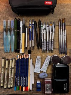 an assortment of pens, pencils, and other items on a wooden table top