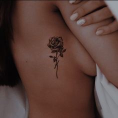 a woman's chest with a rose tattoo on her left side ribcage