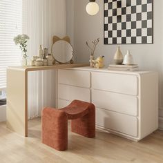 a white dresser with a checkerboard painting on the wall above it and two stools in front of it