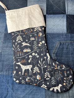 an oven mitt sitting on top of a patchwork piece of denim with trees and animals