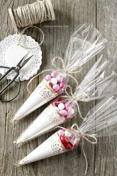 three candy cones wrapped in clear cellophane and tied with twine on wooden table