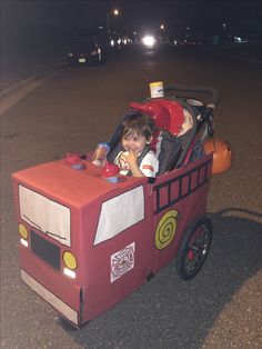 a child in a firetruck costume is sitting in the street with his toys