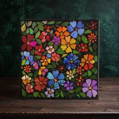 a colorful stained glass painting with flowers and leaves on the outside, in front of a dark green background