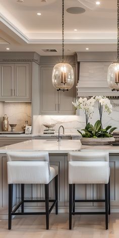 a kitchen with an island and two stools in front of the center island, surrounded by white flowers