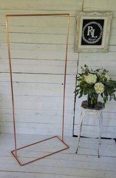 a vase with white flowers sitting on top of a table next to a metal frame