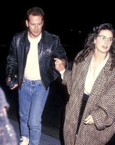 a man and woman walking down the street holding hands