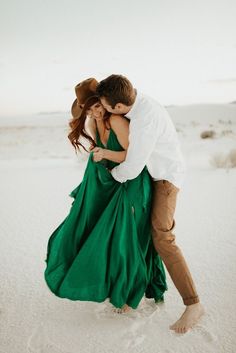 a man and woman are hugging in the sand with their heads close to each other