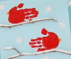 two handprinted red birds sitting on a branch with snowflakes in the background