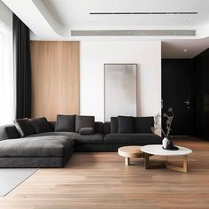 a modern living room with wood flooring and black couches in front of a large window