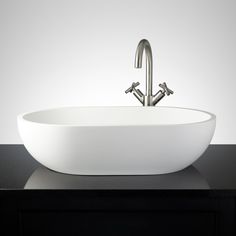 a large white bowl sink sitting on top of a black counter next to a faucet