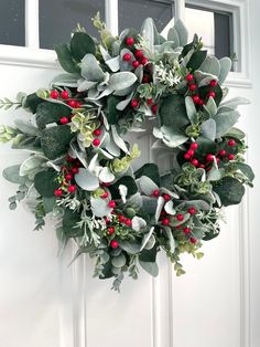 a wreath with red berries and green leaves hanging on the front door, ready to be decorated for christmas