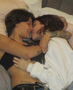 two women laying in bed with their arms around each other as they share a kiss