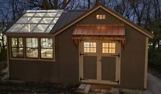 a small shed with a glass roof and windows on the side, lit up at night