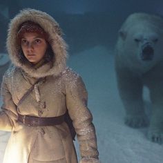 a woman standing in the snow next to a polar bear and holding a light bulb