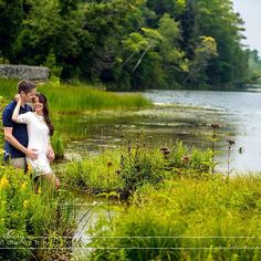 a man and woman standing next to each other near water