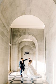 a bride and groom are dancing in an old stone building with black and white checkered floor