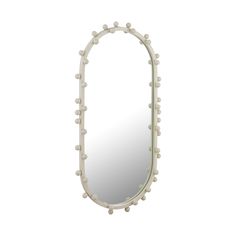 an oval mirror with white balls on the edges and a light colored frame, in front of a white background