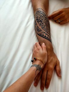 two people holding each other's hands on top of a white sheet covered bed