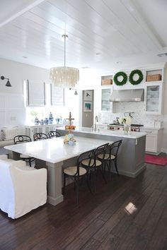 an open kitchen and dining room with white walls, hardwood floors, and wood flooring