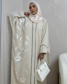 *SUMMER 2024 COLLECTION* This gorgeous Beige butterfly-cut abaya made of Premium Linen Blend is perfect for this summer. It features handmade white embroidery, black piping that gives a beautiful frame to the abaya, buttons for closure and complimented by our Signature Lazer (ليزر) Chiffon. Our Summer Collection comes limited.  The sizes refer to the length of the abaya (in inches) from shoulder down.  The model is 5ft4 tall and wears size 54.  Abaya Material: Premium Linen Blend (not Organic) S Spring Long Abaya With Floral Embroidery, Spring Abaya With Floral Embroidery, Spring Floral Embroidered Long Abaya, Spring Floral Embroidered Abaya, Spring White Embroidered Abaya, Elegant White Summer Abaya, White Long Sleeve Abaya With Floral Embroidery, Elegant White Abaya For Spring, White Spring Abaya