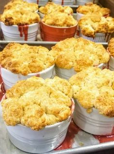 several baked desserts sitting on top of a metal pan covered in red sauce and crumbs