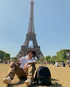 a man sitting on the ground in front of the eiffel tower, paris