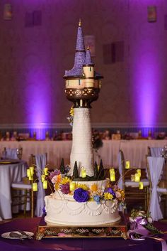 a wedding cake is decorated with purple and yellow flowers on the tablecloths, along with candles