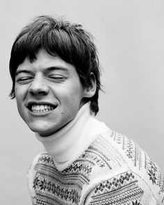 a black and white photo of a young man with his eyes closed, wearing a sweater