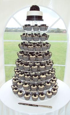 cupcakes in black and white designs are stacked on top of each other with a cake server