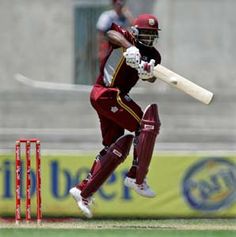 a man swinging a cricket bat on top of a field