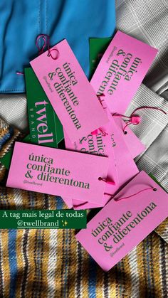 some pink tags that are on top of a plaid blanket and blue shirt with the word new written in spanish