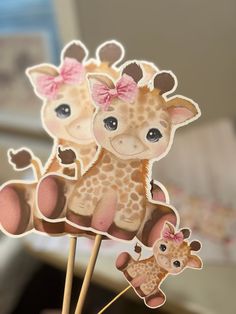 two baby giraffes are sitting on top of each other with pink bows