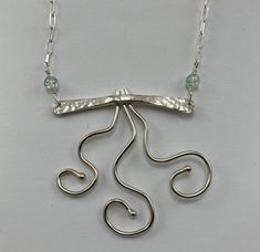 "Sterling silver necklace, hand-formed and hammered from sterling silver wire with green cracked glass bead accents. Pendant is 1.75\"x 1.75\" with attached 20.5\" sterling silver chain, NS1001, Diana Hart" Green Sterling Silver Hammered Jewelry, Green Hammered Sterling Silver Jewelry, Sterling Necklaces, Silver Wire, Sterling Silver Necklaces, Sterling Silver Chains, Silver Necklace, Glass Beads, Jewelry Necklace Pendant