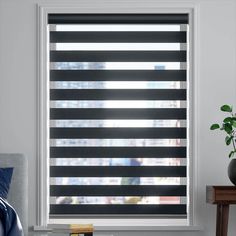 a living room with a couch, table and window covered in blinds that have horizontal shades on them