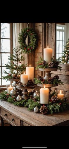 candles are arranged on a table with evergreen and pine cones