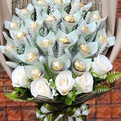 a bouquet of white roses and chocolates in front of a brick wall