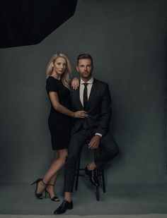 a man and woman sitting on a chair in front of a photo studio with an umbrella