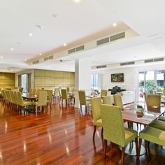 a large dining room with wooden floors and green chairs