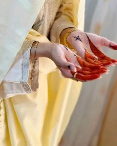 a woman holding carrots in her hands while wearing a white dress and gold jewelry